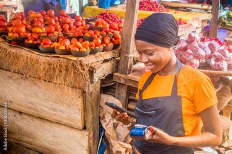 Young African Woman Selling In A Local African Market Holding A Mobile