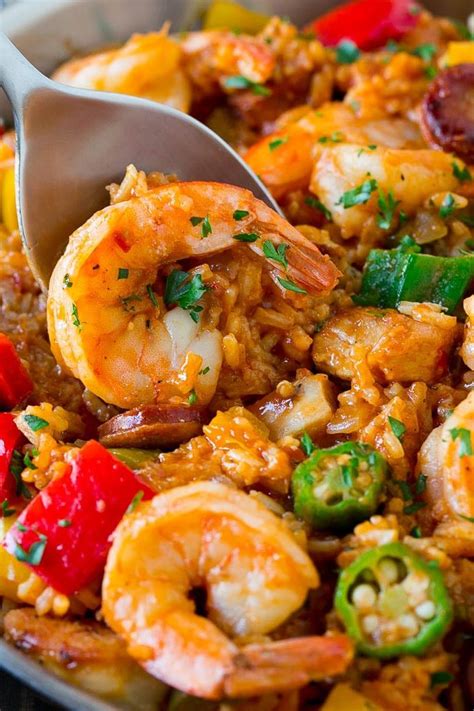 A Spoon Scooping Up Some Food Out Of A Pan With Shrimp And Peppers On It