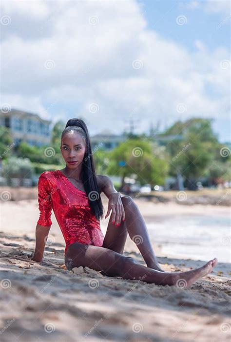 Portrait Of Beautiful Caribbean Adult Teen In Barbados Wearing Red Bikini And Sitting On A