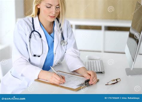 doctor woman at work while sitting at the desk in hospital or clinic blonde cheerful physician