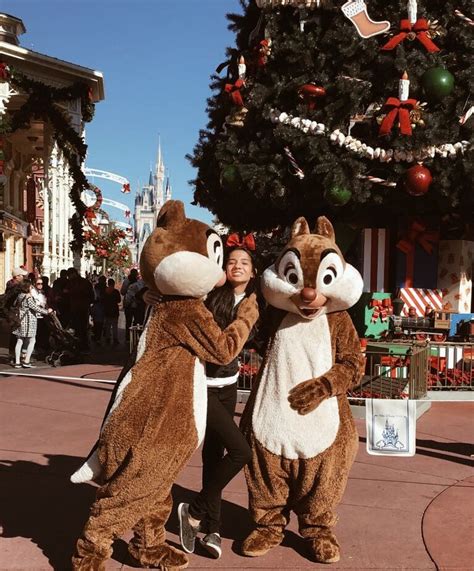 Two People Dressed As Chipmuns In Front Of A Christmas Tree At Disney World