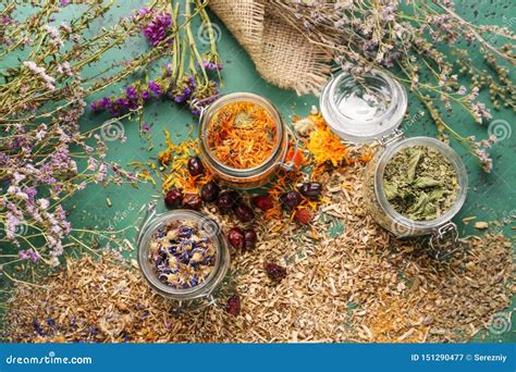 Jars With Aromatic Dried Herbs And Flowers On Color Table Stock Image