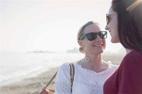 Affectionate Lesbian Couple On Sunny Beach Togetherness Listening Stock Photo