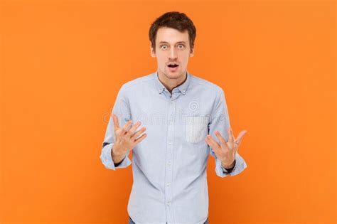 Shocked Unhappy Young Adult Man Standing With Raised Hands Asking What