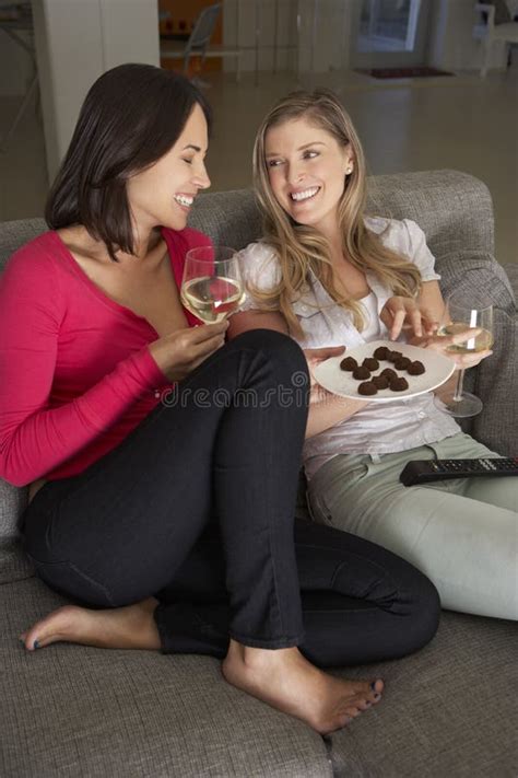Two Women Sitting On Sofa Watching Tv Drinking Wine Stock Photo Image
