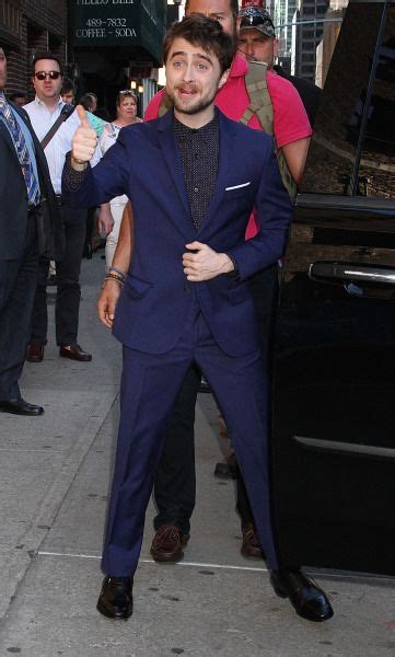 A Man In A Blue Suit And Tie Giving The Thumbs Up Sign While Standing On A Sidewalk