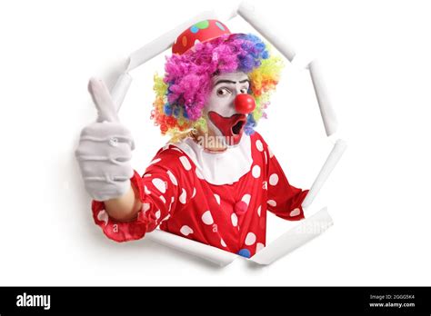 Cheerful Clown Peeking Through A Paper Hole And Gesturing Thumbs Up
