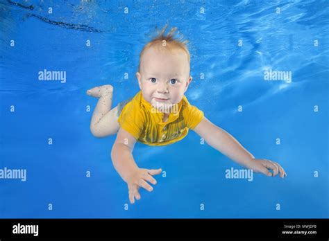 Little Boy In A Yellow Shirt Learns To Swim Underwater In The Pool