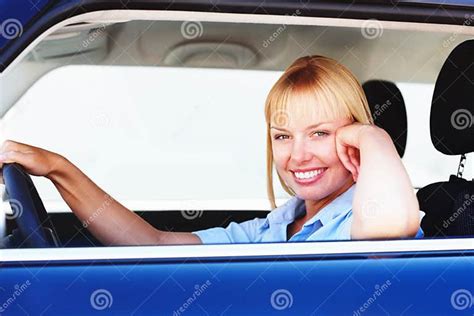 pretty woman smiling from the drivers seat of a car smiling blond woman in a car sitting at the