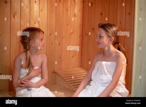 zwei mädchen haben sich in handtücher gewickelt und sitzen in einer finnischen sauna