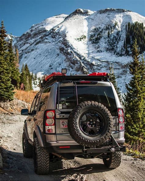 A Jeep Driving Down A Dirt Road In Front Of A Snow Covered Mountain