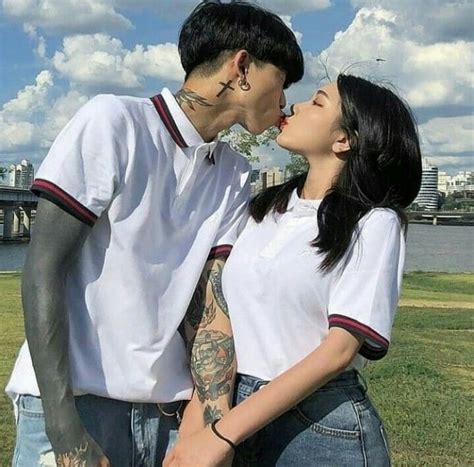 Two People Standing Next To Each Other With Tattoos On Their Faces And Noses One Kissing The Other