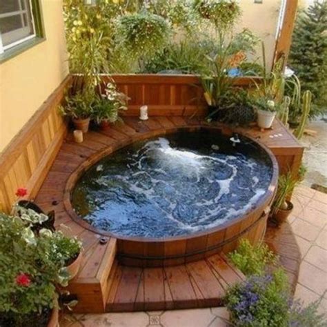 An Outdoor Hot Tub Surrounded By Plants And Potted Plants On The Side