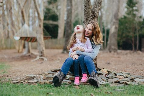 Mother And Daughter Sitting By The Foot Of A Tree Laughing And Smiling By Stocksy Contributor