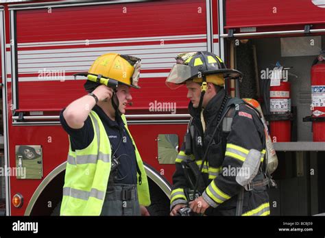 Two Firefighters Talking In Front Of The Pumper Engine At A Fire Scene