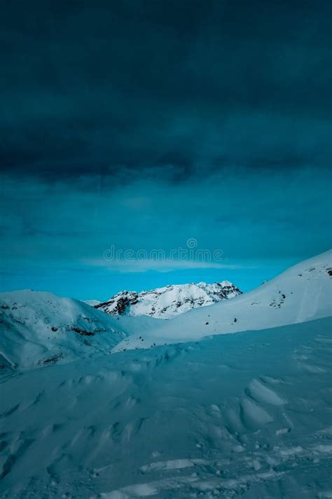 Vertical Shot Of Snow Covered Mountain Under Cloudy Blue Skies Stock