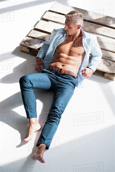 High Angle View Of Sexy Adult Man With Unbuttoned Shirt Lying On Wooden