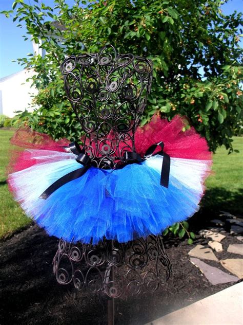 A Blue And Red Tutu Skirt Is Hanging On A Metal Stand In Front Of A Tree
