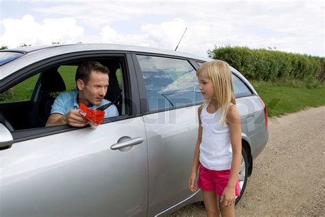 A Male Stranger In A Car Trying To Lure A Girl With Candies Stock