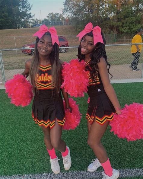 Two Girls In Cheerleader Outfits Posing For The Camera