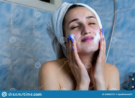close up portrait of smiling brunette girl cleaning her cheeks with purifying foam isolated on