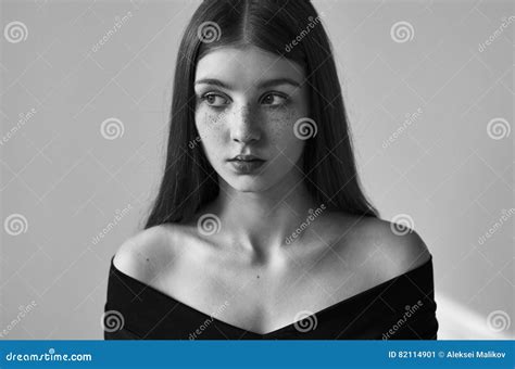 retrato preto e branco dramático de uma menina só bonita com sardas em um fundo branco no tiro