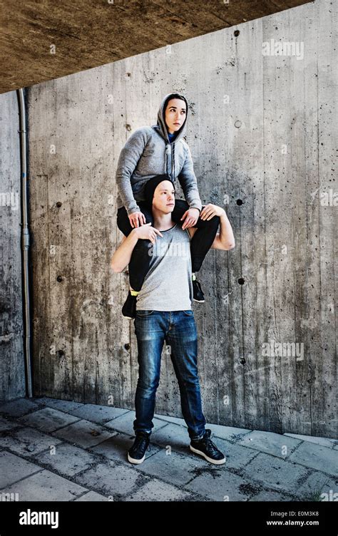 Portrait Of Young Man Carrying Woman On His Shoulders In Urban Setting