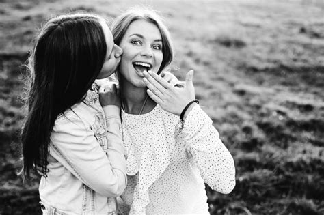 premium photo girl kissing her friend in the cheek and another girl close your mouth with hand
