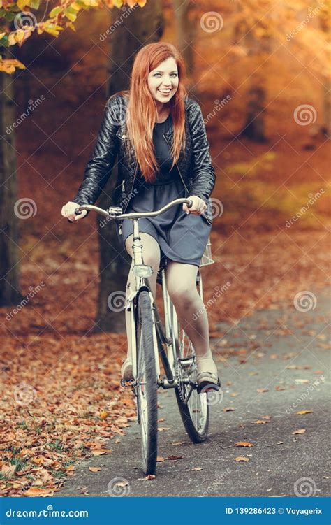 Equitação De Cabelo Vermelha Da Menina Na Bicicleta No Parque Outonal