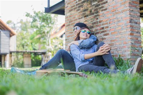Hipster Man Playing Guitar For His Girlfriend Outdoor Against Brick Wall Enjoying Together