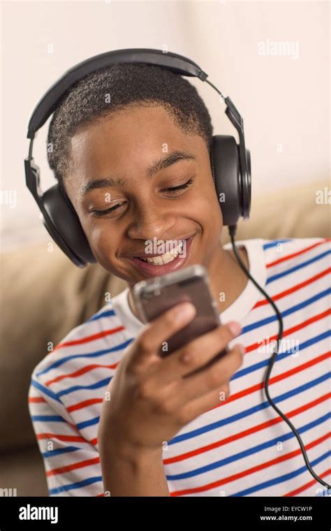 Teenage Boy Wearing Headphones Reading Smartphone Texts Stock Photo Alamy