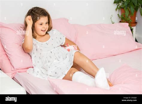 Une adolescente à l esprit positif se trouve sur un lit dans une coulée sur sa jambe avec une