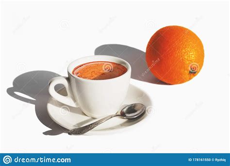 White Cup Of Coffee And An Orange On White Background With Hard Shadows