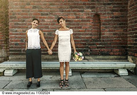 Happy Newlywed Lesbian Couple Standing Against Brick Wall Happy Newlywed Lesbian Couple Standing