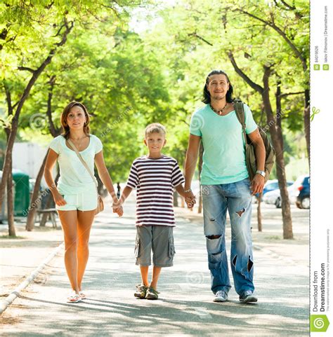 Счастливая семья из трех человек при подросток идя в парк Стоковое Фото изображение