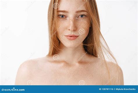 close up shot of attractive feminine naked redhead woman with freckles posing over gray