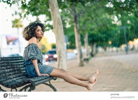 Barefoot Black Woman With Afro Hairstyle Sitting On A Bench A Royalty
