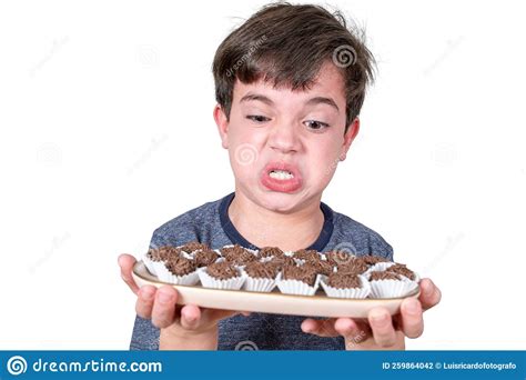 9 year old brazilian holding a tray with several brazilian fudge balls and making an angry face