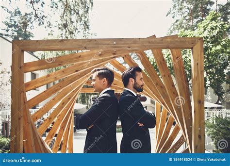 Two Men Standing With Their Backs To Each Other Next To The Wooden