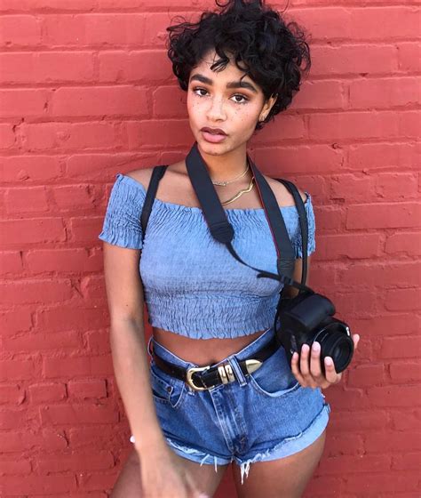 Stunningly Gorgeous Woman Poses Sassily With A Black Camera In A Blue Shortsleeve Silky Midriff