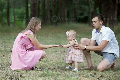 Husband Wife And Their Little Daughter For A Walk In The Park Happy Dad And Mom Teach A One