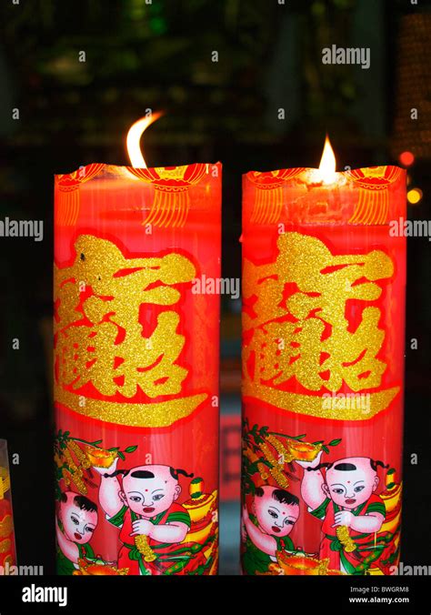 Two Brightly Decorated Chinese Candles Burn In A Temple In Shanghai