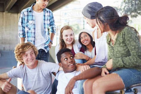 Gang of teenagers hanging out in urban environment. Teenage friends hanging out talking at skate park - Stock ...