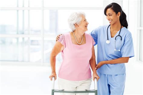 Nurse Assisting Elderly Woman With Walker While Looking At Her Safe