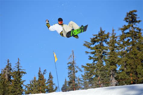 A Man Flying Through The Air While Riding A Snowboard In Front Of Some