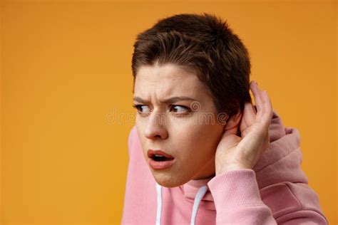 Young Girl Doing Listen Gesture With Hand On Ear Over Yellow Background