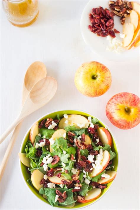 An Apple Salad With Nuts And Feta Cheese In A Green Bowl Next To Two