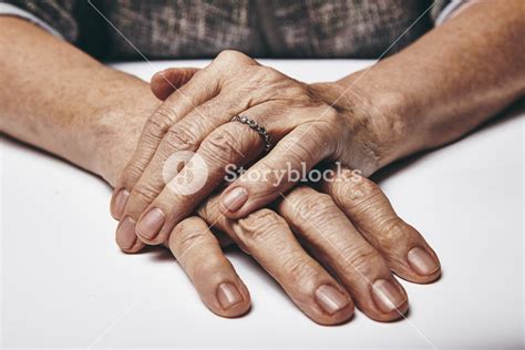 Macro Of An Old Lady Sitting With Her Hands Clasped On A Table Elderly