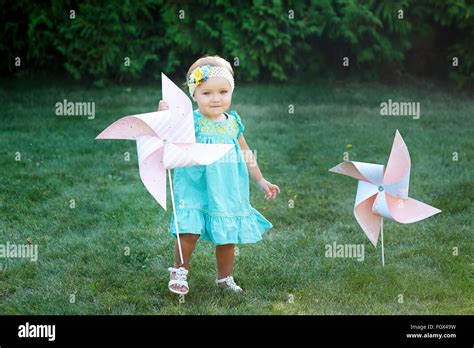 Happy Smiling Little Girl Standing On Meadow And Holding Toy White