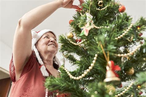 Happy Mature Latin Woman Smiling While Decorating Her Christmas Tree At